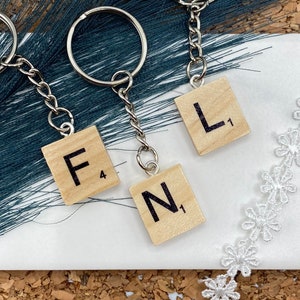 May include: Three silver keychains with wooden Scrabble tiles attached. The tiles spell out "FUN".