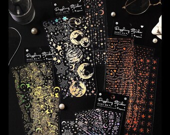 May include: A collection of decorative stickers with celestial and floral designs. The stickers feature gold, silver, and iridescent foil accents. Text on the stickers reads "Dazzling Sticker" and "Your destiny can be your doom."