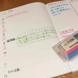 May include: A white notebook with a weekly planner and a to-do list. The notebook has a green, yellow, and pink colored border. The to-do list includes items like "Note names", "Eat less", "Organize thoughts", and "Stretch". The weekly planner has a note about a headache and a note about a new schedule book. The notebook is open to September 9th.