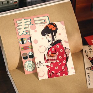 K&ouml;nnte beinhalten: Zwei Vintage-Postkarten mit japanischen Illustrationen. Die erste Postkarte zeigt eine Frau in einem roten Kimono mit wei&szlig;en Blumen, und die zweite Postkarte zeigt einen roten Briefkasten mit einem M&auml;dchen in einem wei&szlig;en Kleid und einer roten Schleife.
