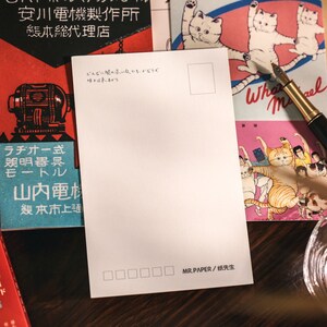 K&ouml;nnte beinhalten: Eine leere wei&szlig;e Postkarte mit einem kleinen Rechteck in der oberen rechten Ecke. Die Postkarte tr&auml;gt den Text "MR.PAPER/纸先生" unten. Die Postkarte liegt auf einer Holzoberfl&auml;che mit anderen Gegenst&auml;nden.