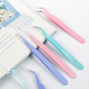 May include: Four pairs of tweezers with slanted tips. The tweezers are in different colors: pink, blue, light blue, and turquoise.