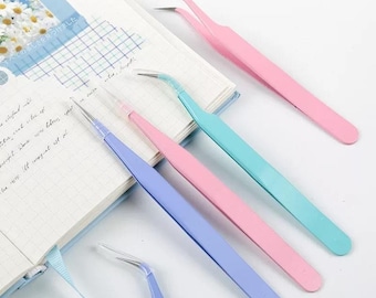 Può includere: Quattro paia di pinzette con punte inclinate. Le pinzette sono di diversi colori: rosa, blu, azzurro e turchese.