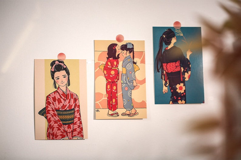 K&ouml;nnte beinhalten: Drei gerahmte Illustrationen von Frauen in traditioneller japanischer Kleidung, bekannt als Kimonos. Die Kimonos sind in verschiedenen Farben und Mustern, darunter Rot, Blau und Schwarz. Die Illustrationen sind auf einem cremefarbenen Hintergrund gedruckt.