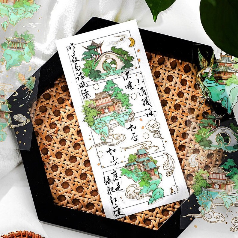 Pu&ograve; includere: Un foglio di adesivi trasparenti con un design da giardino cinese tradizionale. Gli adesivi sono in uno schema di colori verde e oro e includono testo in caratteri cinesi.