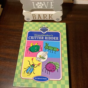 May include: A green book with a checkered pattern on the cover. The title is "Grandmother's Kitchen Wisdom Critter Riddler" with a cartoon illustration of a bug on the cover. The author is Dr. Myles H. Bader.