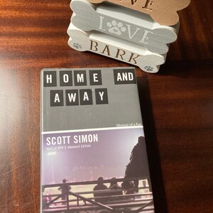 May include: A book titled "Home and Away: Memoir of a Fan" by Scott Simon, host of NPR's Weekend Edition. The book cover features a black and white photo of people sitting in bleachers at a sporting event.