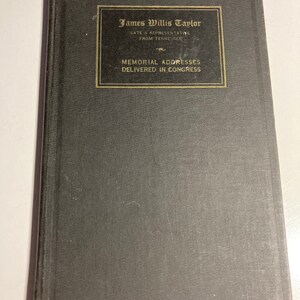 May include: A black hardcover book with gold lettering on the front cover. The title reads "James Willis Taylor, Late a Representative from Tennessee, Memorial Addresses Delivered in Congress".