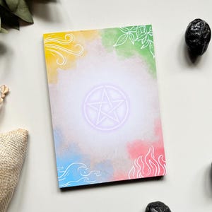 May include: A rectangular card with a pentagram in the center, surrounded by watercolor-style splashes of color. The corners feature white line art representing wind, leaves, waves, and fire. Two black stones are on the right side. The card is likely used for divination.
