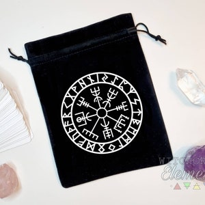 May include: Black velvet pouch with a white compass design and runes around the edge. The pouch is closed with a drawstring.