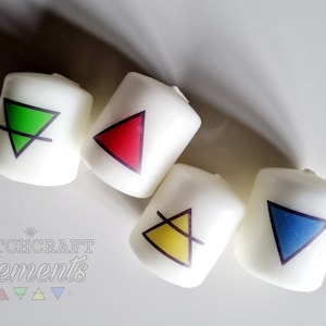 May include: Four white candles with colourful triangle designs in green, red, yellow, and blue. The candles are arranged on a white surface. The text "Witchcraft Elements" is visible in the lower left corner.