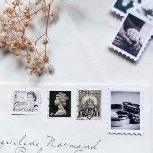 Puede incluir: Un sobre blanco con una dirección escrita a mano a Jacqueline Normand, Vernice Parkways Apt., East Aureliohaven, Pensilvania. El sobre tiene varios sellos, incluyendo un sello canadiense con un retrato de la reina Isabel II, un sello húngaro con un edificio y un sello con una foto de anillos de boda.