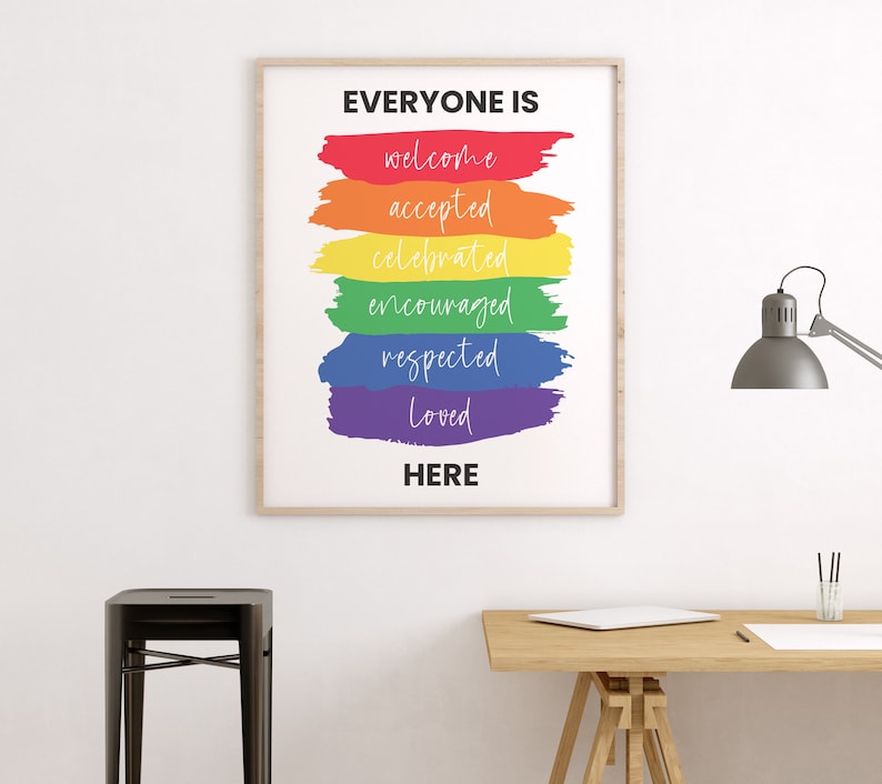 K&ouml;nnte beinhalten: Ein gerahmter Druck mit dem Text "Jeder ist willkommen, akzeptiert, gefeiert, ermutigt, respektiert, geliebt hier" in einem Regenbogen-Farbschema. Der Regenbogen besteht aus Pinselstrichen.