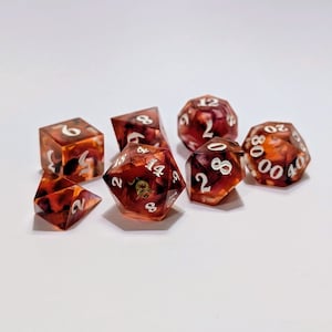 May include: A set of six polyhedral dice with a red, brown, and white marbled appearance. The dice are numbered 2, 4, 6, 8, 12, and 20.