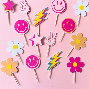 Può includere: Un set di 12 topper per cupcake colorati con vari design, tra cui simboli di pace, facce sorridenti, fulmini e fiori. I topper sono realizzati in carta e sono perfetti per aggiungere un tocco divertente e festoso a qualsiasi festa.