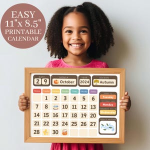 Könnte beinhalten: Ein lächelndes Kind hält einen gerahmten, bedruckbaren Kalender. Der Kalender ist auf Oktober 2024 datiert und hat ein Herbstthema. Der Kalender misst 28 cm x 22 cm und enthält den Text "Easy Printable Calendar".