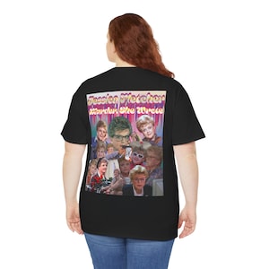Puede incluir: Camiseta negra con un gráfico colorido de Jessica Fletcher del programa de televisión "Se ha escrito un crimen". El gráfico es un collage de la cara de Jessica Fletcher y otros personajes del programa. El texto "Jessica Fletcher Se ha escrito un crimen" está impreso en una fuente retro.