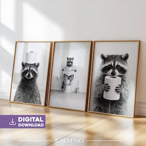 Puede incluir: Juego de tres impresiones artísticas de mapaches en blanco y negro enmarcadas. Un mapache tiene un rollo de papel higiénico en la cabeza, otro lee un periódico en un inodoro y el tercero sostiene un rollo de papel higiénico. Las impresiones están etiquetadas como "DESCARGA DIGITAL".