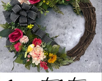May include: A spring-themed wreath with pink, red, and yellow flowers, green leaves, and a black and white bow. The wreath is made of twigs and has the text "Sweet Stems Wreath Company" at the bottom.