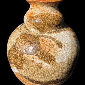 May include: A handcrafted ceramic vase with a bulbous body and a narrow neck. The vase features a speckled, earthy color palette of tan, brown, and orange, with a glossy finish. The design is organic and textured, suitable for home decor.