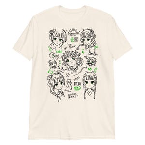 May include: Cream-colored short-sleeve t-shirt featuring a black and green anime-style illustration. The design includes multiple anime character portraits, Japanese text, and decorative elements. The shirt is made of a soft, comfortable material.