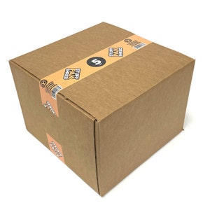 May include: A brown cardboard box with a label that says "Stuff Pak Shred" and a number "5" on it. The box is sitting on a white surface.