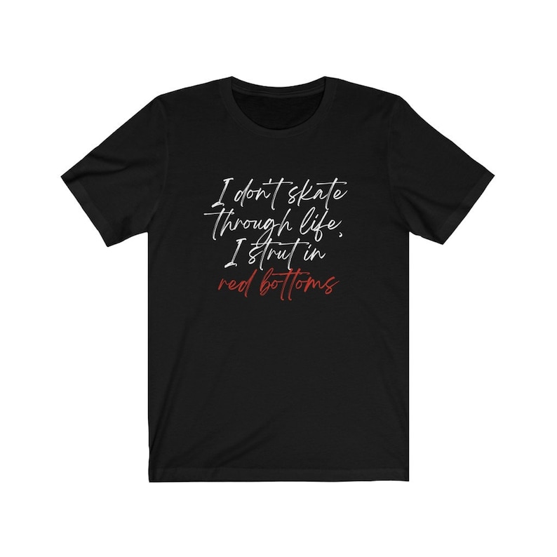 以下が含まれることがあります： 黒いTシャツに白い文字で「人生をスケートすることはない、赤い靴で歩くんだ」と書かれている。