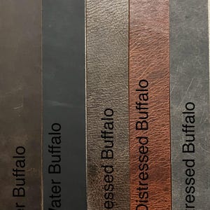 May include: Five leather swatches in different colors and textures. The swatches are labeled "Zyhorse Water Buffalo", "Black Matte Water Buffalo", "Chocolate Distressed Buffalo", "Antique Distressed Buffalo", and "Gray Distressed Buffalo".