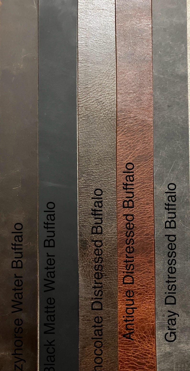 May include: Five leather swatches in different colors and textures. The swatches are labeled "Zyhorse Water Buffalo", "Black Matte Water Buffalo", "Chocolate Distressed Buffalo", "Antique Distressed Buffalo", and "Gray Distressed Buffalo".