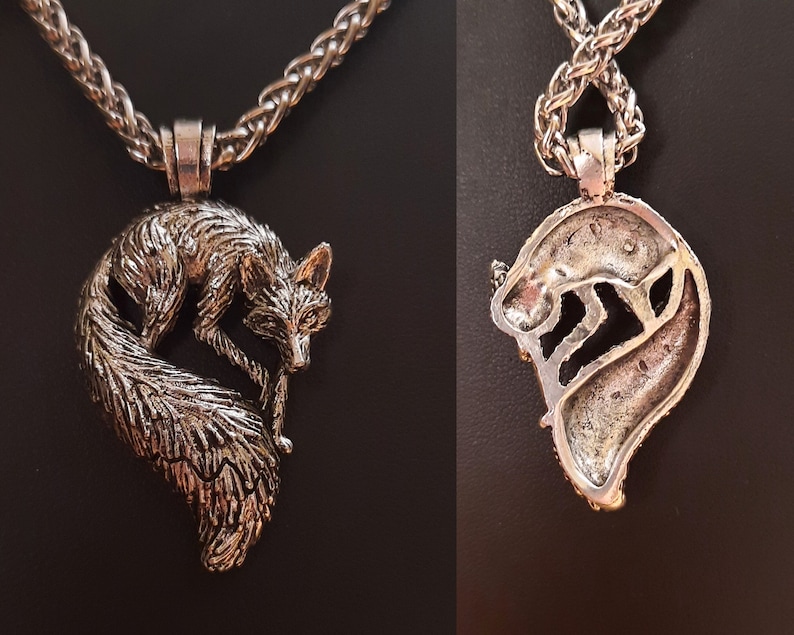 Puede incluir: Un collar de plata con un colgante de zorro con un dise&ntilde;o detallado. El zorro est&aacute; enroscado con la cola envuelta alrededor de su cuerpo. El collar est&aacute; en una cadena de plata.