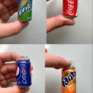 May include: Four miniature soda can charms, each featuring a different brand: Sprite, Coca-Cola, Pepsi, and Fanta Orange. The charms are silver with a pull tab and are made to look like real soda cans.