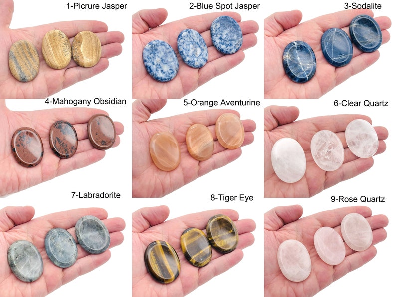 Peut inclure: Neuf types de pierres polies de forme ovale, chacune avec une couleur et un motif uniques. Les pierres sont dispos&eacute;es en trois rang&eacute;es de trois, chaque pierre &eacute;tant tenue dans une main. Les pierres sont &eacute;tiquet&eacute;es avec leurs noms, tels que "Picture Jasper", "Blue Spot Jasper" et "Sodalite".