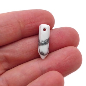 Pode incluir: Pingente de mármore branco e cinza com um furo no topo, em forma de oval pontiagudo.
