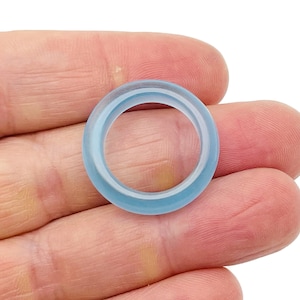 Może przedstawiać: Jasnoniebieski pierścionek wykonany ze szkła. Pierścionek jest gładki i ma polerowane wykończenie.
