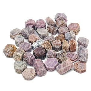 Peut inclure: Une collection de cristaux de rubis bruts, roses, rouges et bruns. Les cristaux sont de tailles et de formes variées, certains ayant une forme plus arrondie et d'autres une forme plus pointue.