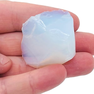 Könnte beinhalten: Ein weißer, undurchsichtiger Opal-Kristall mit einer rauen, unregelmäßigen Form. Der Kristall ist durchscheinend und hat einen leichten irisierenden Schimmer.