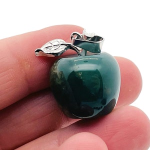 May include: A green agate apple pendant with a silver leaf and stem. The pendant is approximately 2.5 cm in diameter.