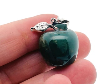 May include: A green agate apple pendant with a silver leaf and stem. The pendant is about 1 inch in diameter.