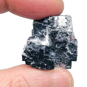 May include: A black and silver crystal cluster with a cubic shape. The crystal is a natural mineral specimen.