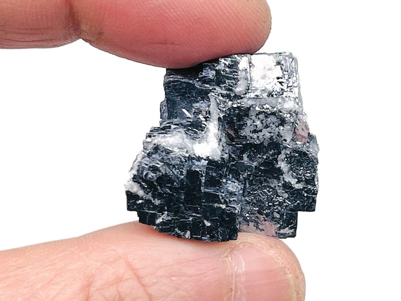 May include: A black and silver crystal cluster with a cubic shape. The crystal is a natural mineral specimen.