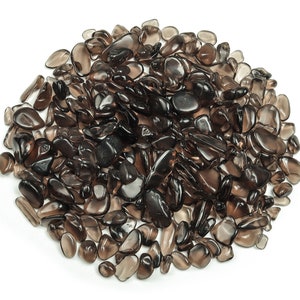 Pode incluir: Um grande monte de lascas de quartzo fumado, também conhecido como topázio fumado, em vários tamanhos e formas. As lascas são de cor marrom escura e têm uma aparência translúcida.