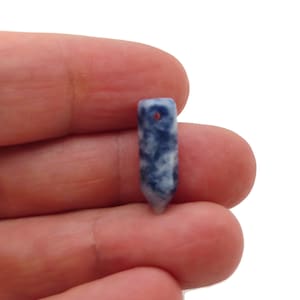 Könnte beinhalten: Ein kleiner, spitzer Steinanhänger in Blau und Weiß mit einem Loch oben zum Aufziehen.