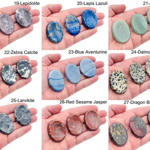 Peut inclure: Un ensemble de neuf paires de pierres polies de forme ovale, chaque paire pr&eacute;sentant un type de pierre diff&eacute;rent. Les pierres sont dispos&eacute;es en trois rang&eacute;es de trois paires, avec le nom des pierres indiqu&eacute; au-dessus de chaque paire. Les pierres sont toutes lisses et polies, et elles pr&eacute;sentent une vari&eacute;t&eacute; de couleurs et de motifs.