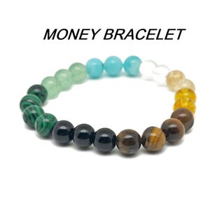 May include: A multi-colored beaded bracelet with green, blue, black, brown, and gold beads. The bracelet is called "MONEY BRACELET".
