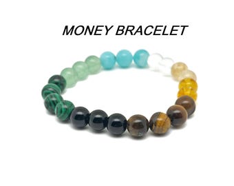 May include: A multi-colored beaded bracelet with green, blue, black, brown, and gold beads. The bracelet is called "MONEY BRACELET".