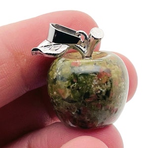 Op de afbeelding: Een groene, bruine en rode gevlekte stenen appelbedel met een zilveren metalen steel en blad.