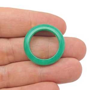 Op de afbeelding: Een felgroene ring van jade. De ring is glad en gepolijst, met een eenvoudig, rond ontwerp.