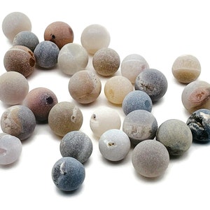 Könnte beinhalten: Eine Sammlung von 20 Achatperlen in verschiedenen Brauntönen, Grautönen und Weißtönen. Die Perlen sind glatt und poliert und haben ein natürliches, organisches Aussehen.