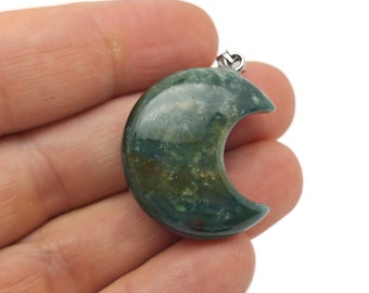 May include: Green moss agate crescent moon pendant with a silver bail.