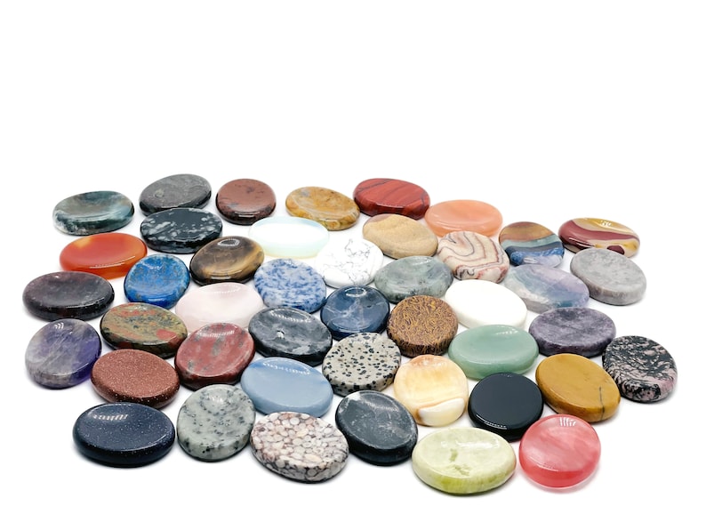 Peut inclure: Une collection de pierres polies de forme ovale de diff&eacute;rentes couleurs et motifs. Les pierres sont dispos&eacute;es en cercle sur un fond blanc.